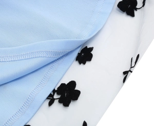 Detail of light blue knit fabric stitched with white mesh and black floral patterns