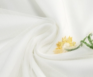 Close-up of intricate sunflower embroidery on white mesh fabric for French floral dress