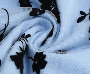 Close-up of light blue mesh fabric with black flocked floral patterns and soft texture
