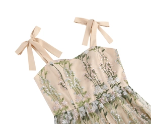 Detailed embroidery on champagne dress featuring floral patterns and bow shoulder straps