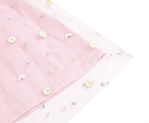 Detailed macro view of pink tulle fabric featuring white daisy floral embroidery and soft lining