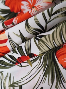 Détail macro d'imprimé floral tropical sur tissu blanc avec des feuilles de palmier
