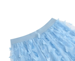 Dettaglio di gonna in tulle azzurro con farfalle 3D e vita elastica in tinta unita