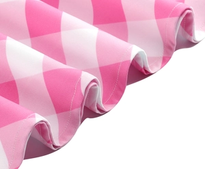 Détail du tissu vichy rose et blanc montrant des coutures précises et l'ourlet ondulé