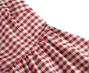 Detailed close-up of pink gingham fabric featuring waist seams and pleated stitching details