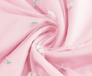 Detailed macro view of pink tulle fabric with delicate floral embroidery and green leaves