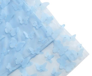 Dettaglio del tessuto a rete azzurro con farfalle 3D applicate e ricami in argento lucido