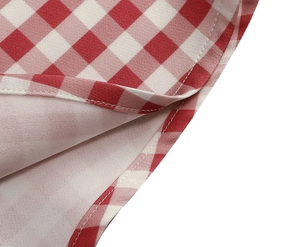 Detailed view of pink plaid dress fabric with fine stitching and hemline texture