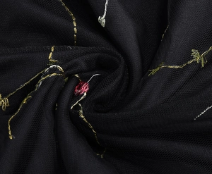 Detailaufnahme von schwarzem Netzstoff mit goldener und silberner Blumenstickerei aus Metall