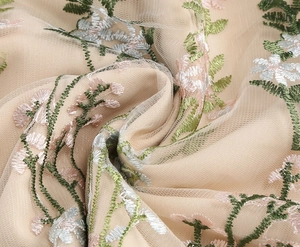 Close-up of premium champagne mesh fabric with intricate floral embroidery and leaf patterns