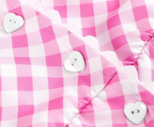 Detail of pink gingham dress featuring scalloped edges and three white heart buttons