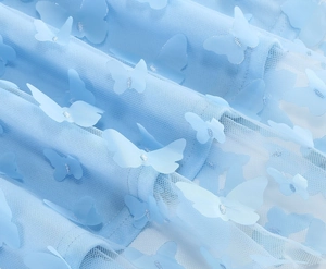 Vista dettagliata del tessuto a rete azzurro con squisite applicazioni di farfalle 3D e glitter
