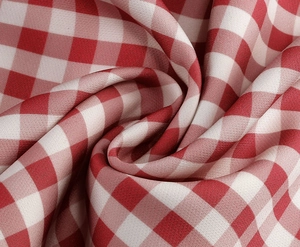 Macro shot of red and white gingham fabric with detailed spiral drape and weave texture