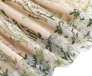 Detailed close-up of floral embroidery on light apricot mesh vintage party dress fabric