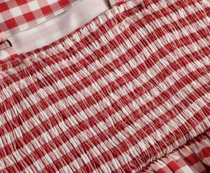 Detail of pink gingham dress featuring elastic smocking and adjustable shoulder strap