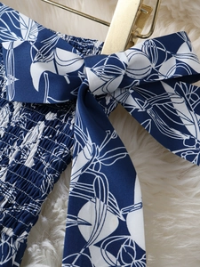 Détail de robe imprimé floral bleu avec smocks élastiques et nœud décoratif élégant