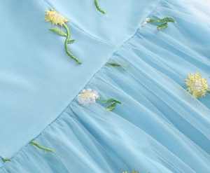 Detailed view of light blue mesh fabric with delicate daisy floral embroidery and tulle