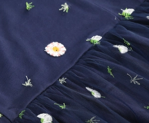 Detail of floral daisy embroidery on dark blue mesh and pleated tulle fabric
