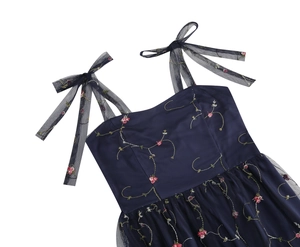 Nahaufnahme von dunkelblauem Netzkleid mit rosa Blumenstickerei und Schulterschleifen