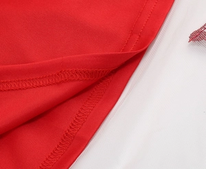 Close-up of red fabric stitching with layered white mesh tulle on a girl's dress skirt