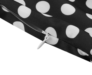 Detail view of invisible zipper closure and white polka dot print on black retro dress