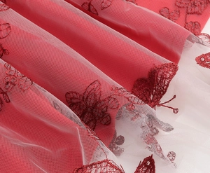 Detail showing red butterfly embroidery on mesh fabric of the girl's party dress