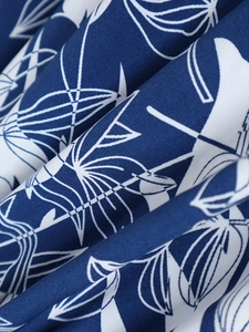 Gros plan sur tissu bleu foncé avec imprimés de feuilles tropicales blanches et texture