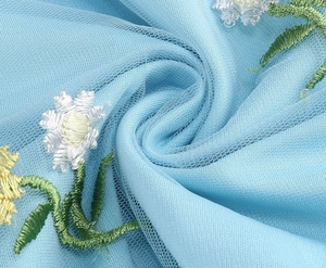Detail of light blue mesh fabric with delicate white and yellow daisy floral embroidery