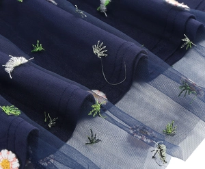 Macro shot of navy blue tulle mesh with delicate floral embroidery and layered inner lining