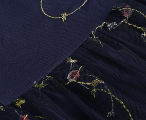 Detail der Blumenstickerei und des plissierten Netzes am dunkelblauen Vintage-Kleid