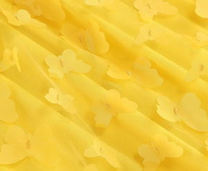Dettaglio delle applicazioni a farfalla 3D su tessuto in tulle a rete giallo limone