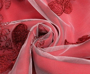 Close-up of red mesh fabric featuring intricate floral embroidery on the girl dress