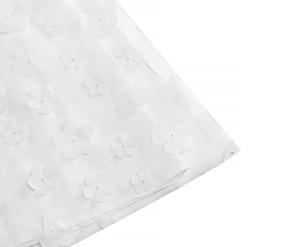 Detailed close-up of white mesh fabric featuring elegant 3D floral lace appliques