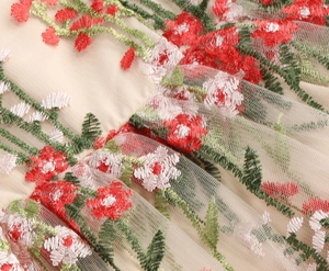 Close-up of intricate red and white floral embroidery on premium beige mesh fabric