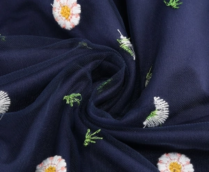 Detailed macro view of white daisy embroidery on dark blue mesh fabric dress