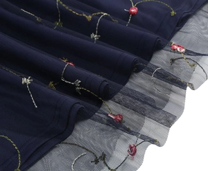 Detail der Blumenstickerei auf dunkelblauem Kleid mit transparentem Spitzennetz am Saum