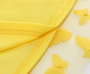 Dettaglio della gonna in tulle giallo con applicazioni di farfalle 3D e rifiniture cucite