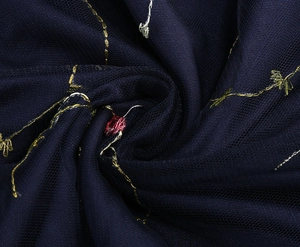 Detailansicht von dunkelblauem Netzstoff mit feiner Gold- und Rotstickerei-Verzierung