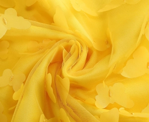 Dettaglio macro del tessuto in rete gialla con applicazioni di farfalle 3D vivaci