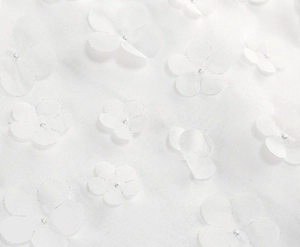 Detailed close-up of white mesh fabric featuring delicate 3D floral appliques and silver glitter