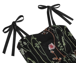 Detail of floral embroidery on black dress with satin bow shoulder straps