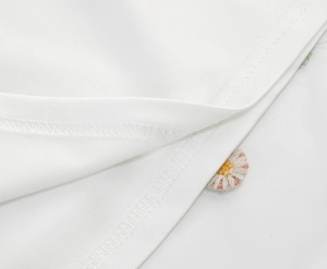 Macro shot of embroidered daisy detail on white mesh floral French sundress fabric