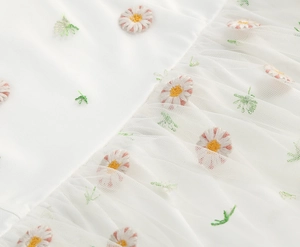 Detail of floral daisy embroidery on multi-layered mesh fabric for French style dress