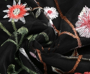 Macro detail of intricate floral embroidery on premium black tulle fabric for party dress