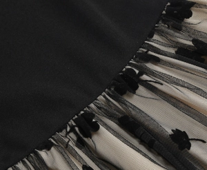 Detail of black floral flocking on tulle fabric with contrast beige lining of a dress