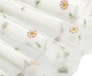 Close-up of white mesh fabric with daisy embroidery and layered tulle texture