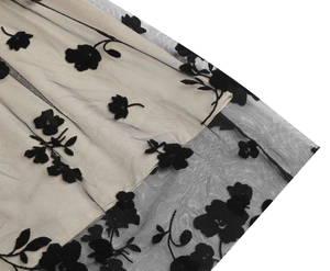 Detailed macro view of black floral flocked mesh fabric with beige contrast lining on dress