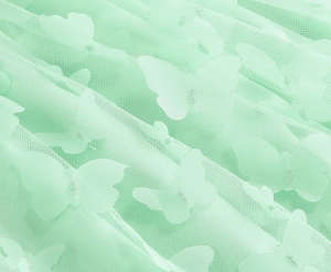 Dettaglio di tessuto a rete verde menta con farfalle 3D e ricami su una gonna a trapezio