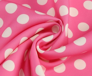 Dettaglio del tessuto rosa a pois che mostra il drappeggio morbido e la trama liscia