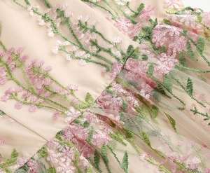 Macro detail of delicate floral embroidery on champagne sheer mesh fabric with silk lining